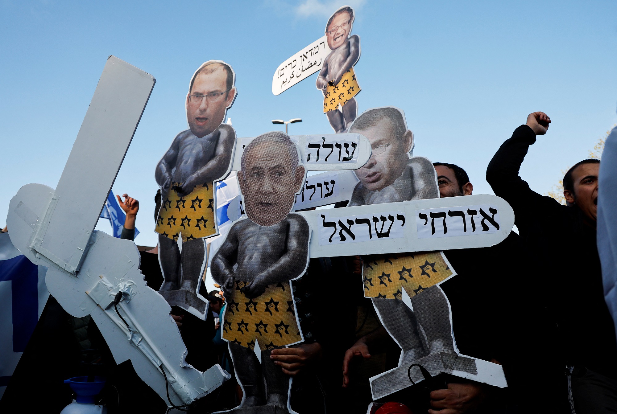 Protesters hold signs with the heads of Israeli Prime Minister Benjamin Netanyahu, Minister of National Security Itamar Ben-Gvir, Knesset member Simcha Rothman and Deputy Prime Minister and Minister of Justice Yariv Levin, as they attend a demonstration after Prime Minister Netanyahu dismissed the defense minister and his nationalist coalition government presses on with its judicial overhaul, in Jerusalem, March 27, 2023. REUTERS/Ammar Awad